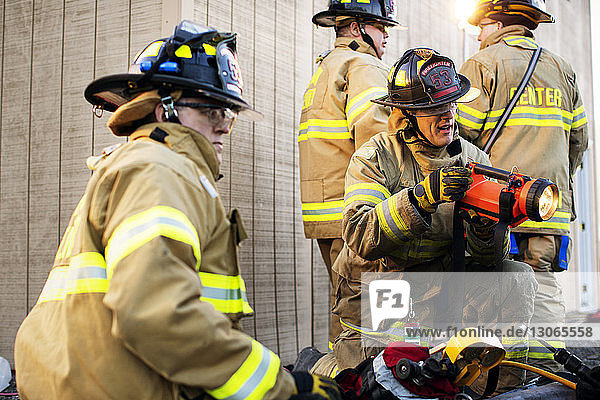 Feuerwehrmann hält Taschenlampe  während seine Kollegen im Einsatz sind