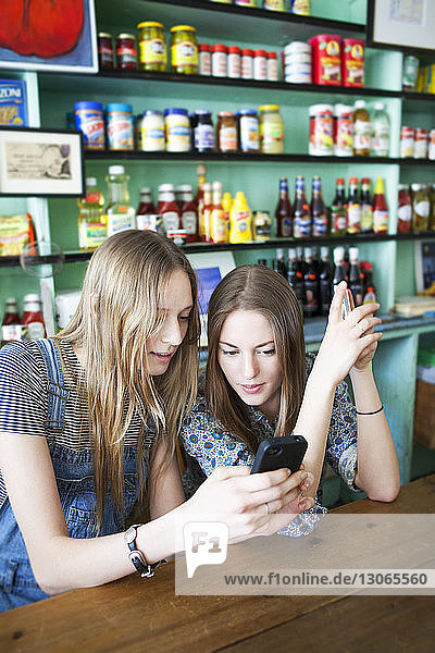 Freunde schauen auf Handy  während sie im Laden sitzen