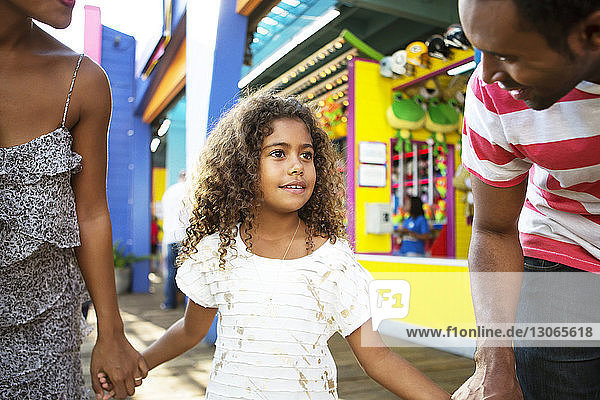 Father looking at girl with mother while standing in amusement park