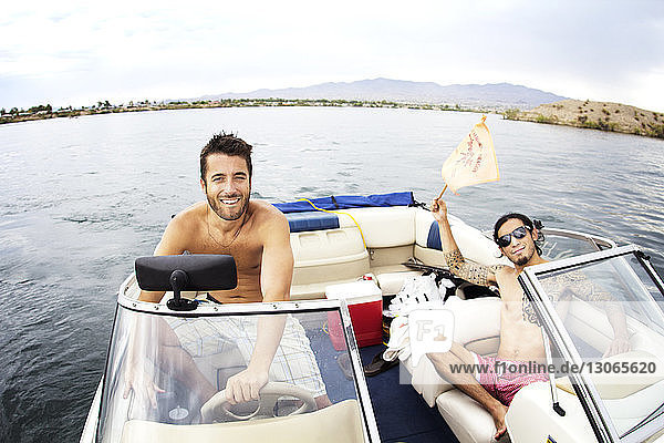 Porträt von Freunden  die im Motorboot auf dem See sitzen