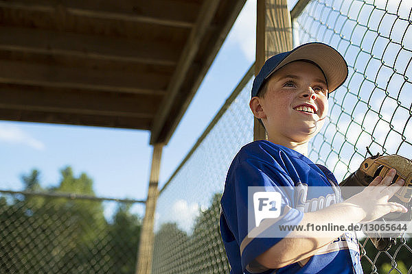 Low angle view of happy boy standing in dugout