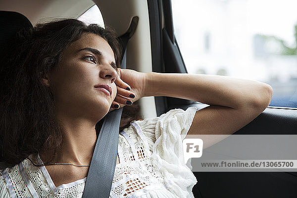 Nachdenkliche Frau schaut weg  während sie im Auto unterwegs ist