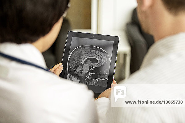 Rückansicht von Ärzten  die Röntgenbilder im Tablet-Computer betrachten