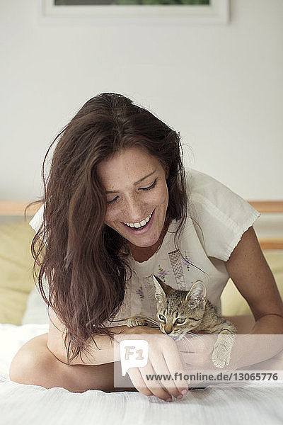 Frau sieht Katze an  während sie auf dem Bett sitzt