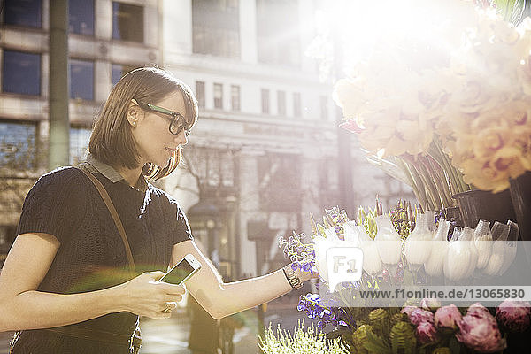 Frau betrachtet Blumen im Geschäft auf der Straße in der Stadt