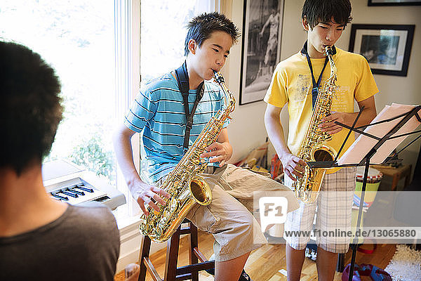 Siblings practicing saxophones at home