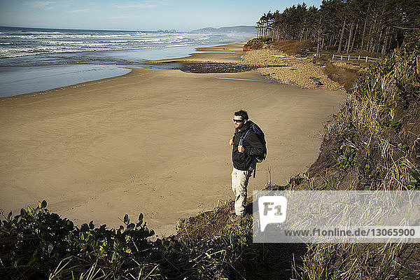 Hochwinkelaufnahme eines Mannes  der auf einer Felsformation am Strand steht