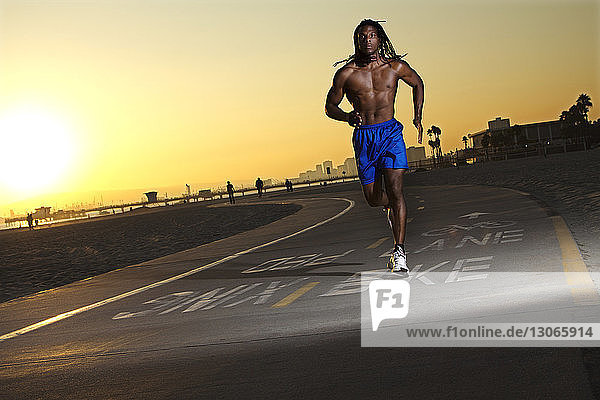 Männlicher Athlet läuft bei Sonnenuntergang auf der Straße