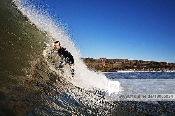 Surfer surfen im Meer vor klarem blauen Himmel