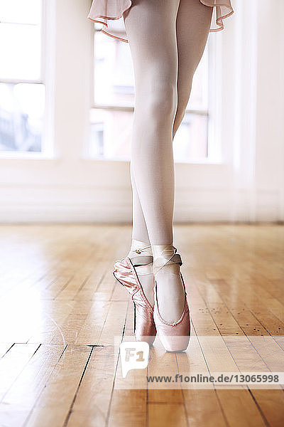 Niedriger Teil der Ballettlehrerin geht auf Zehenspitzen auf Hartholzboden