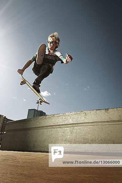 Niedrigwinkel-Ansicht eines Mannes  der mit einem Skateboard gegen den Himmel springt