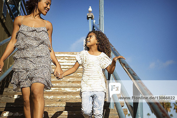 Mutter und Tochter unterhalten sich auf der Treppe gegen den blauen Himmel