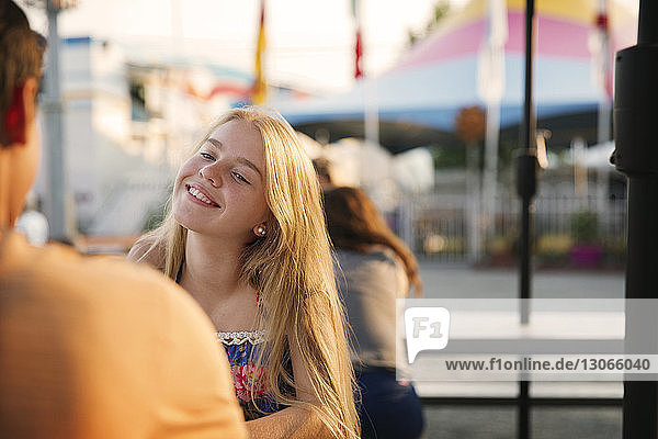 Lächelnder Teenager sitzt mit seinem Freund im Vergnügungspark