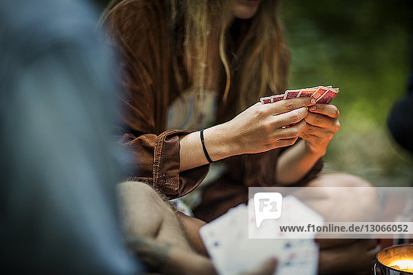 Frau spielt Kartenspiel  während sie auf einer Veranda im Wald sitzt