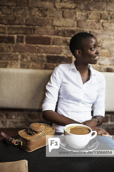 Frau mit heißer Schokolade schaut weg  während sie im Café sitzt