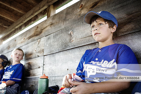 Low angle view of boys sitting in dugout and looking away