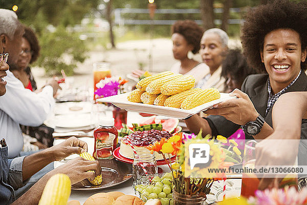 Family enjoying food while sitting at table in backyard
