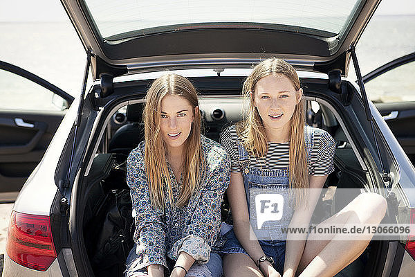 Portrait of women sitting in car trunk