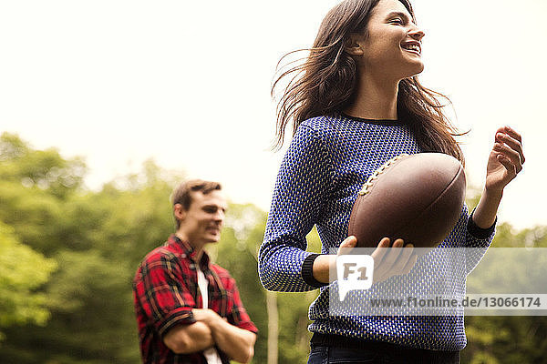 Paar spielt Fussball im Rasen gegen den Himmel