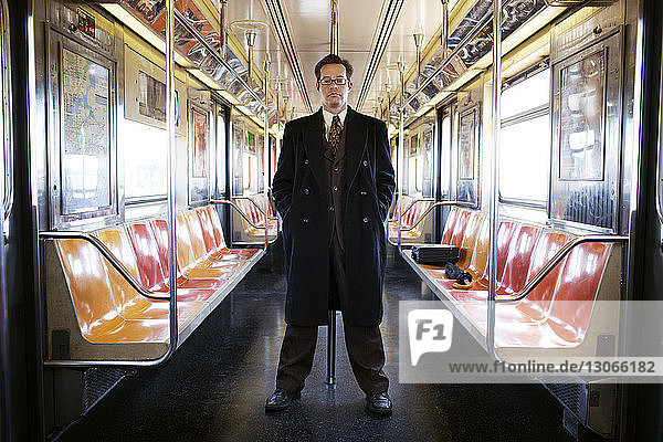 Porträt eines Geschäftsmannes  der im Zug an einer Stange lehnt