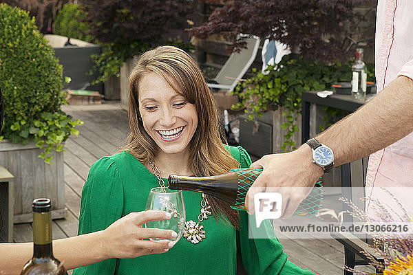 Smiling woman looking at man pouring drink for friend