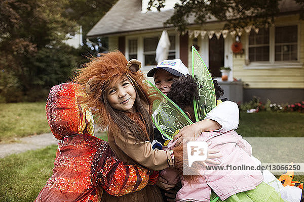 Glückliche Freunde in Halloween-Kostümen umarmen sich im Hof