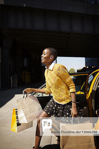 Frau mit Einkaufstaschen steigt aus Taxi aus