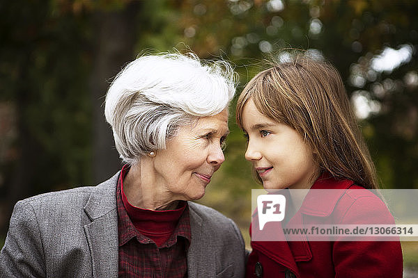 Woman looking at cute granddaughter while relaxing in park