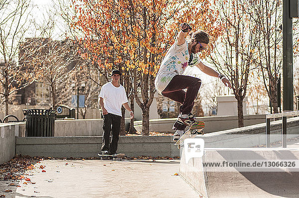 Friends skateboarding on sports ramp at park