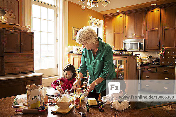 Großmutter mit Kindern bereitet zu Weihnachten zu Hause Kekse zu