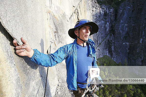 Thoughtful rock climber standing against mountain