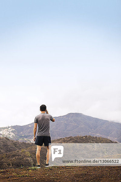 Rear view of athlete talking on mobile phone while standing on mountain