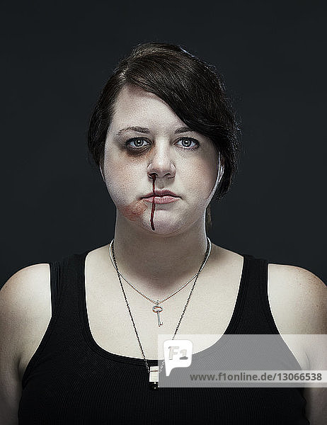 Porträt einer verletzten Frau vor schwarzem Hintergrund stehend