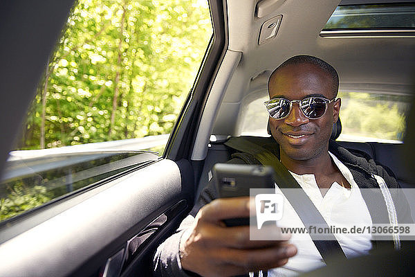 Man using smart phone while traveling in car