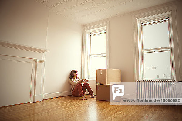 Woman looking away while sitting on floor at new home