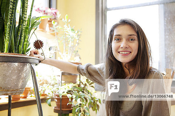 Portrait of smiling woman by potted plant at home