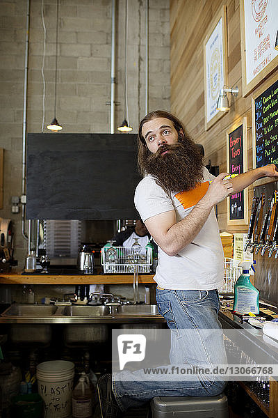 Mann mit Bart steht bei Bierdeckeln in der Brauerei