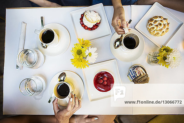 Cropped image of friends having coffee and dessert at table in restaurant