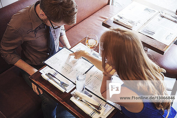 Woman pointing on menu while sitting with boyfriend in restaurant