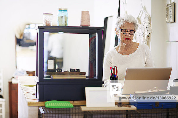 Ältere Frau benutzt Laptop-Computer in einer Boutique