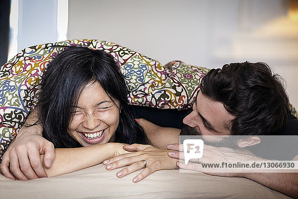 Glückliches Paar unterhält sich zu Hause im Bett liegend