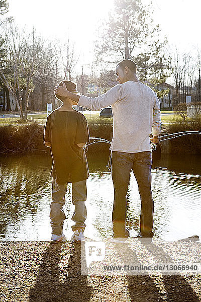 Rückansicht von Vater und Sohn beim Angeln im See