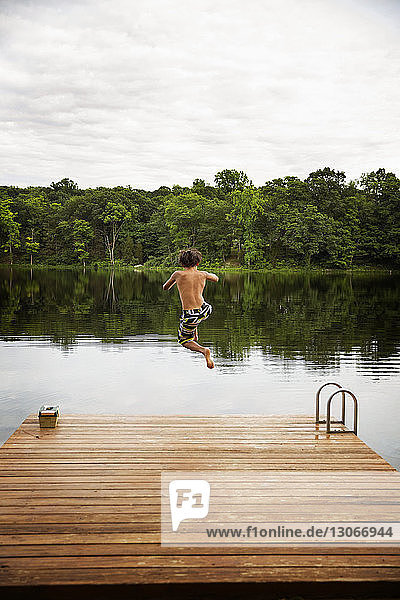 Rückansicht eines Jungen  der im See gegen ein Dock springt