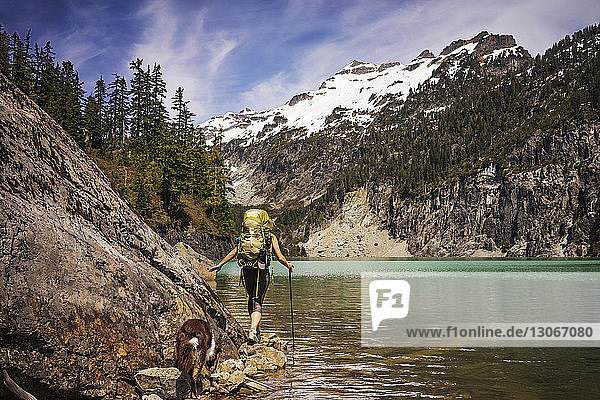 Rückansicht einer Frau mit Hund beim Spaziergang am See