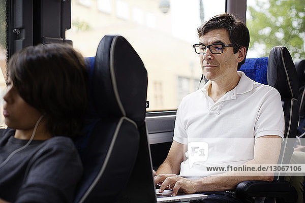 Mann benutzt Laptop-Computer  während er im Bus sitzt
