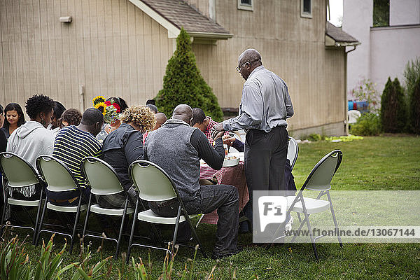 Family praying at breakfast table in lawn