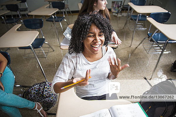 Hochwinkelansicht einer fröhlichen Frau  die im Klassenzimmer sitzt