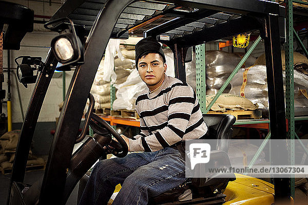 Portrait of man sitting in forklift at warehouse