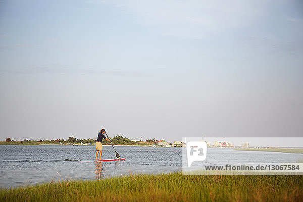 Rückansicht eines Mannes beim Paddelbootfahren im See gegen den Himmel