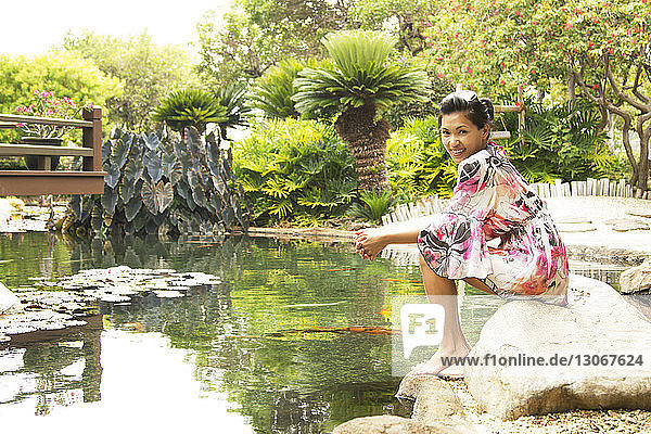 Porträt einer Frau  die auf Felsen in einem Teich in einem Fremdenverkehrsort sitzt
